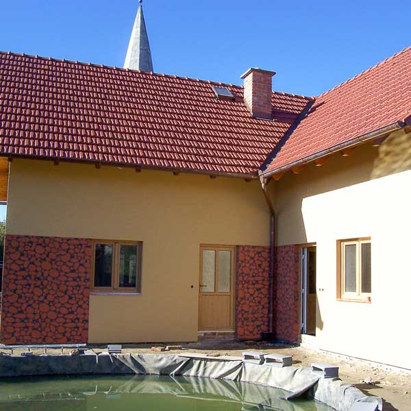 Pohled na dům s okrovou fasádou s ozdobnými částmi kamenného vzhledu
